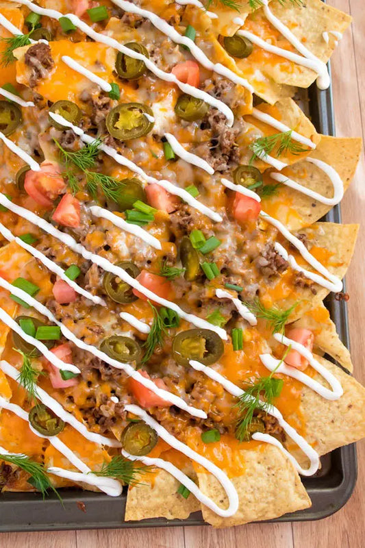 Fully Loaded Nachos with crispy corn chips, creamy cheese sauce, melted shredded cheese, pico de gallo, salsa, jalapeños, sour cream, protein, and house seasonings.