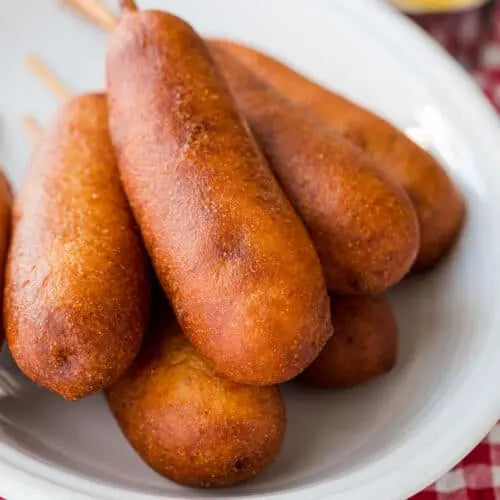 Golden and crispy Halal beef corn dog on a stick, drizzled with smoky chipotle sauce, served on a rustic plate.